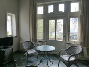 a living room with a table and chairs and windows at Hotel Villa Tosca in Hannover