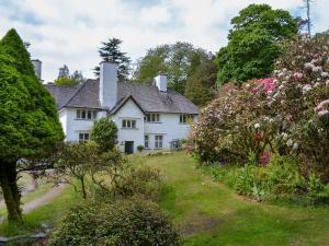 a white house on a hill with flowers at Scafell Apartment in Ambleside