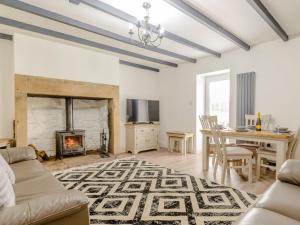 a living room with a fireplace and a table at Kerseycleugh Bridge Cottage in Kielder