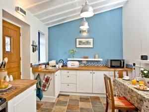 a kitchen with blue walls and a table and chairs at Wheal Holan in Lower Boscaswell