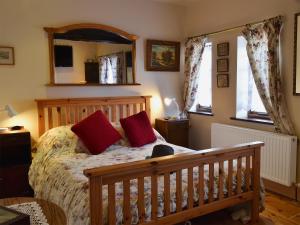 ウールにあるRailway Cottageのベッドルーム1室(赤い枕と鏡付きのベッド1台付)