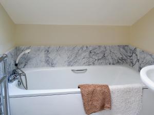 een badkamer met een wit bad naast een wastafel bij Railway Cottage in Wool
