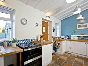 a kitchen with blue and white walls and a stove at Wheal Holan in Lower Boscaswell