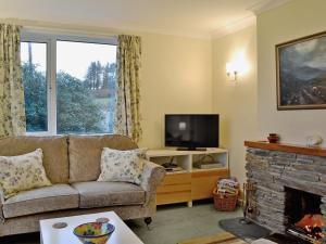 a living room with a couch and a fireplace at Seabank Cottage in Clachan