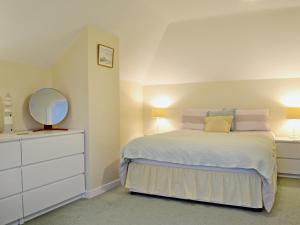a bedroom with a bed with a mirror and a dresser at Seabank Cottage in Clachan