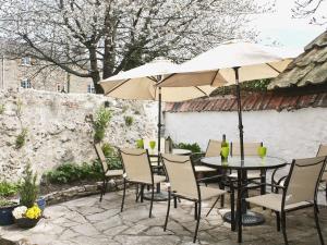 a patio with a table and chairs and an umbrella at Churchview House in Winterborne Abbas