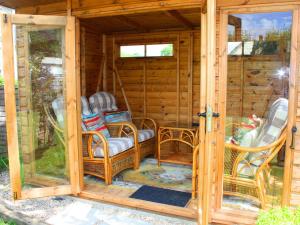 a screened in porch with wicker chairs and a porch at Churchview House in Winterborne Abbas