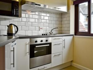 a kitchen with white cabinets and a stainless steel oven at The Stable Loft in Bowness-on-Windermere