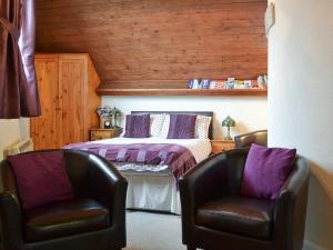 um quarto com duas cadeiras de couro e uma cama em The Stable Loft em Bowness-on-Windermere