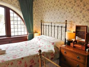 a bedroom with a bed with a dresser and a window at Dunvarlich House in Aberfeldy