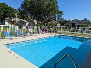 a large swimming pool with chairs and a fence at Peace And Tranquility At Southern Dunes in Haines City