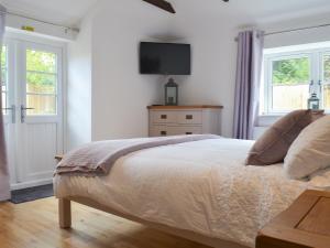 a bedroom with a bed with a tv on the wall at Bluebell Cottage in Nether Stowey