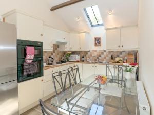 a kitchen with a glass table with chairs and appliances at Bickley School Annexe in Broxa