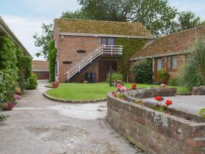 a house with a brick wall and flowers in the yard at Birch Cottage in Cote