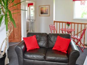 a leather couch with two red pillows in a living room at Hillcroft in Cold Norton