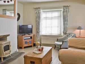 ein Wohnzimmer mit einem TV, einem Sofa und einem Tisch in der Unterkunft Kingsley Cottage in Instow