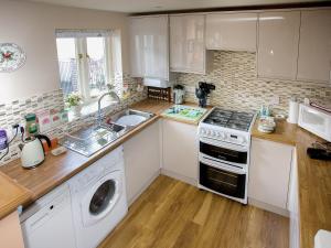 a kitchen with white cabinets and a washer and dryer at Cherry Tree Cottage in Bovey Tracey