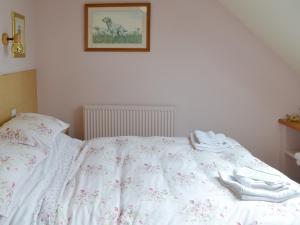 a bed with white sheets and white shoes on it at Cherry Tree Cottage in Bovey Tracey