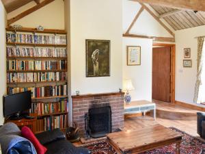 a living room with a fireplace and book shelves filled with books at The Dairy - 17321 in Compton