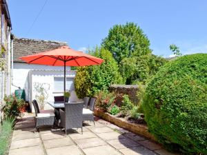 a patio with a table with an umbrella and chairs at Weavers Cottage in Stow on the Wold