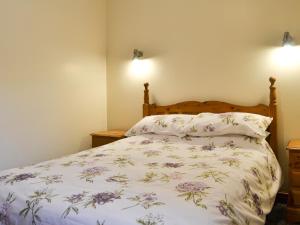 a bedroom with a bed with a floral bedspread at Beudy Bach - 16986 in Brynsiencyn