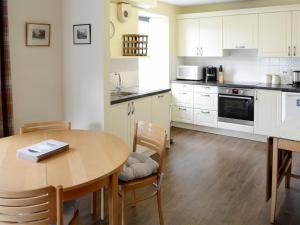a kitchen with a wooden table and a table and chairs at Birch Cottage in Glenrossal