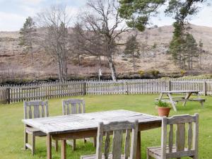 a wooden table and chairs in a yard with a fence at Birch Cottage in Glenrossal