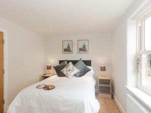 a bedroom with a white bed and two windows at Barn Owl Cottage in Skidby