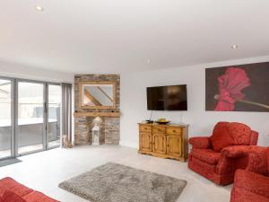 un soggiorno con sedia rossa e TV di Barn Owl Cottage a Skidby