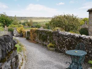 a stone wall with a table next to a stone bench at The Chapel in Kilnsey