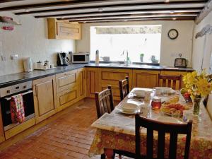 Folly Cottage في Kentisbeare: مطبخ مع طاولة وكراسي ومطبخ مع طاولة