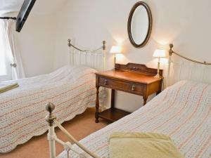 Folly Cottage في Kentisbeare: غرفة نوم بسريرين وطاولة مع مرآة