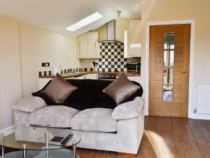 a living room with a couch and a kitchen at Oak Cottage in Winthorpe