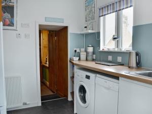 a kitchen with a washing machine and a sink at Boatmans Cottage - 27787 in Portessie