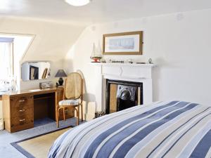 a bedroom with a bed and a desk and a fireplace at Boatmans Cottage - 27787 in Portessie
