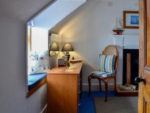 a bedroom with a desk and a bed and a chair at Boatmans Cottage - 27787 in Portessie