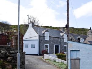 una casa de piedra con garaje blanco en Boatmans Cottage - 27787 en Portessie