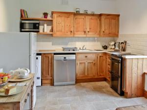 a kitchen with wooden cabinets and stainless steel appliances at Rhydlanfair in Capel Garmon