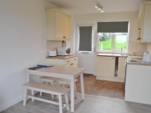 a kitchen with a table and a sink and a microwave at Eider Cottage in Embleton