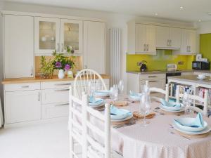 a white kitchen with a table with chairs and a tableablish at Tamar Ten in Gunnislake