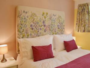 a white bed with two red pillows in a bedroom at Tamar Ten in Gunnislake