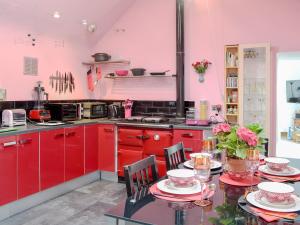 a kitchen with red cabinets and a table with chairs at Sea Yonder in Buckie