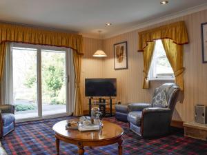 a living room with chairs and a table and a tv at Boatland Lodge in Perth