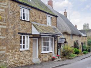 an old brick house with a thatched roof at The Old Sweet Shop in Hook Norton