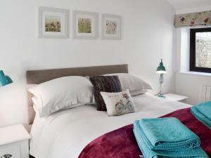 um quarto com uma cama com lençóis brancos e almofadas em Bellhouse Croft em Shelley