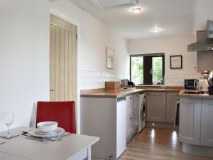 a kitchen with a table and a red chair at Bellhouse Croft in Shelley