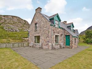 una antigua casa de piedra con una puerta verde y sillas en Rubha Lodge, en Shieldaig