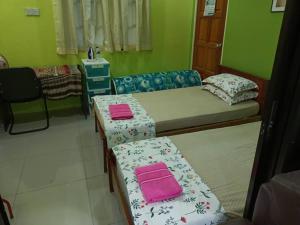 a room with two beds and two tables in it at HOMESTAY JANNATI TAMBUN in Tambun