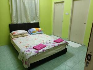 Un dormitorio con una cama con almohadas rosas. en HOMESTAY JANNATI TAMBUN en Tambun