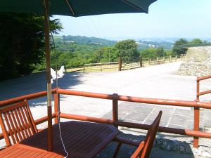 a wooden chair with an umbrella on a balcony at Cider Cottage in Hawkchurch